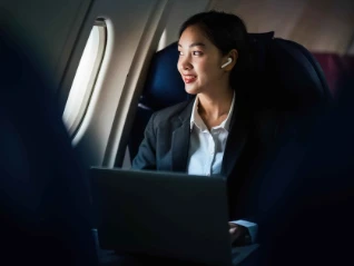 Successful Asian business woman working in airplane cabin during flight small